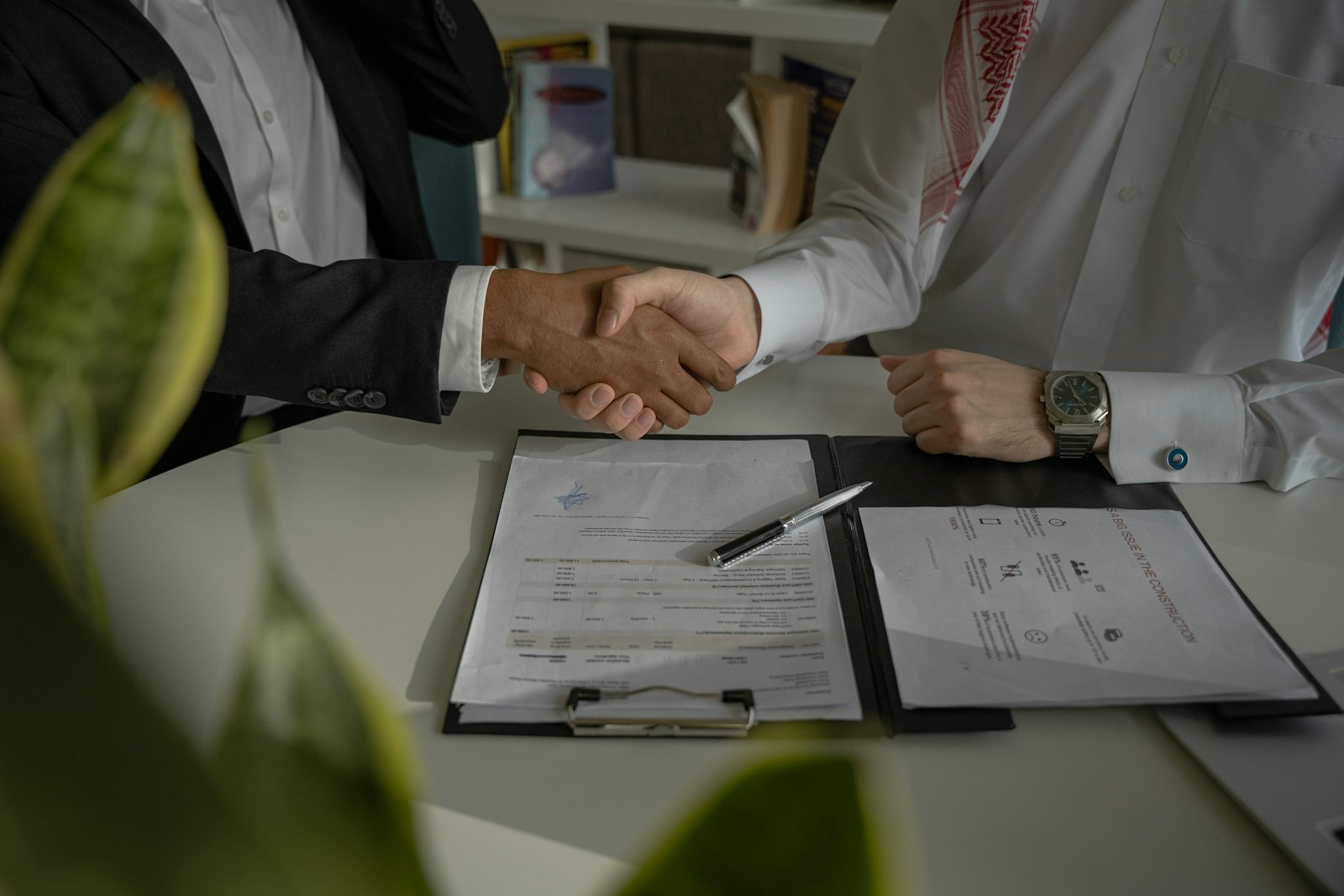 Two people shaking hands over a signed agency contract